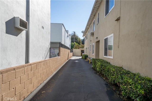 view of property exterior featuring fence, a wall mounted AC, and stucco siding