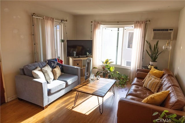 living room featuring a wall unit AC and wood finished floors