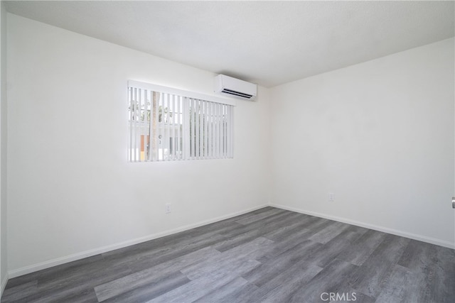 spare room with dark wood-style floors, baseboards, and a wall mounted AC