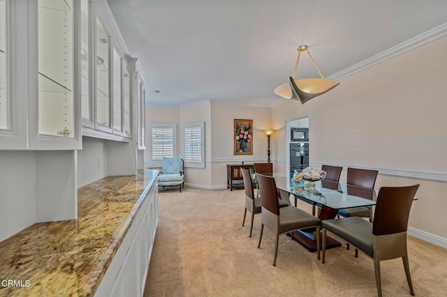 dining room featuring baseboards, light colored carpet, and crown molding