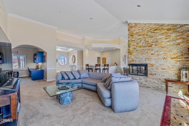 living area featuring arched walkways, a stone fireplace, ornamental molding, and carpet floors