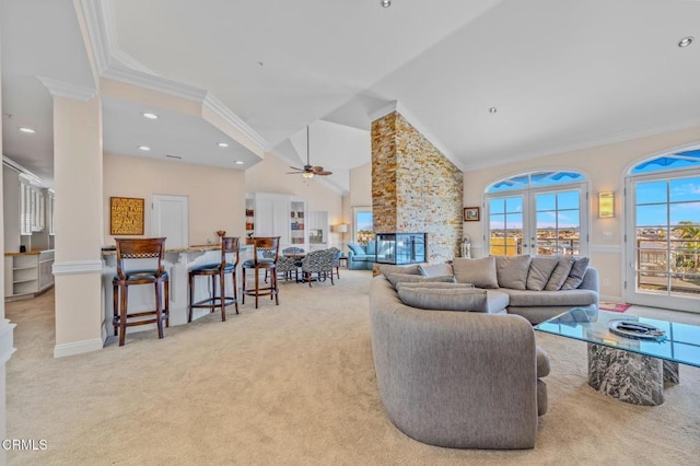 living room featuring ceiling fan, carpet, ornamental molding, a stone fireplace, and high vaulted ceiling