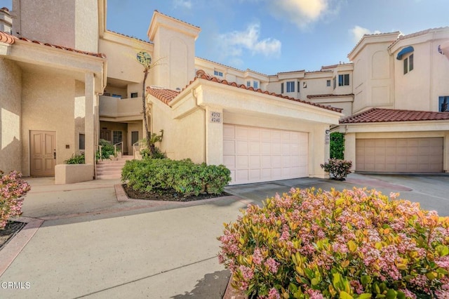 view of front of house featuring stucco siding, a tiled roof, and a garage