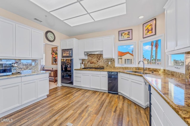 kitchen with built in microwave, a sink, stainless steel gas stovetop, under cabinet range hood, and dobule oven black