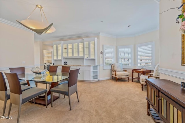 dining room featuring baseboards, washer / clothes dryer, light carpet, and ornamental molding