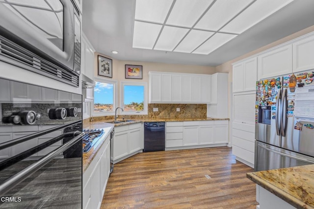 kitchen with a sink, black appliances, and white cabinets