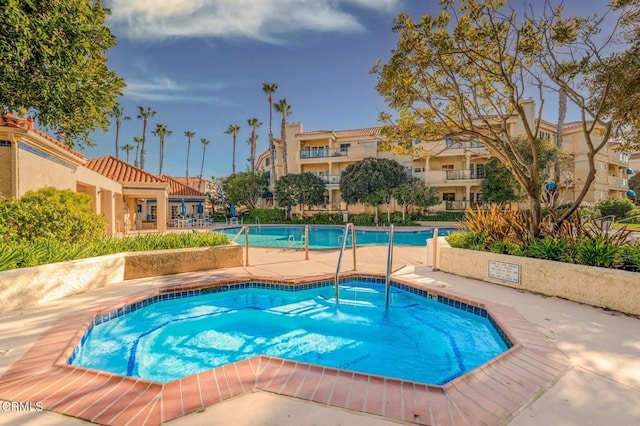 community pool with a patio, a residential view, and a hot tub