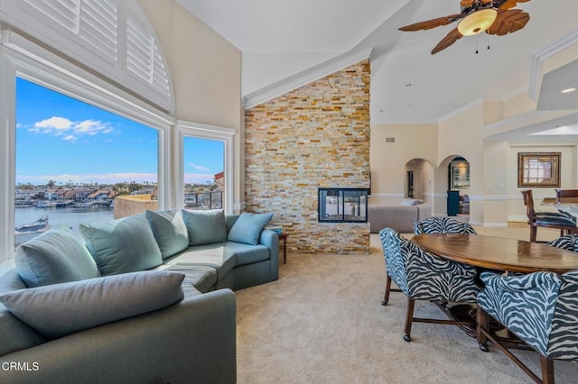 carpeted living room with arched walkways, a healthy amount of sunlight, ornamental molding, and a ceiling fan