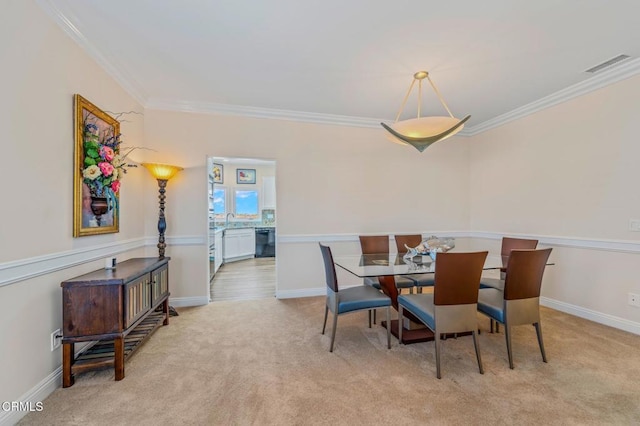 carpeted dining space featuring visible vents, a sink, baseboards, and ornamental molding