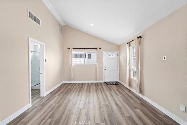 foyer entrance with visible vents, vaulted ceiling, baseboards, and wood finished floors