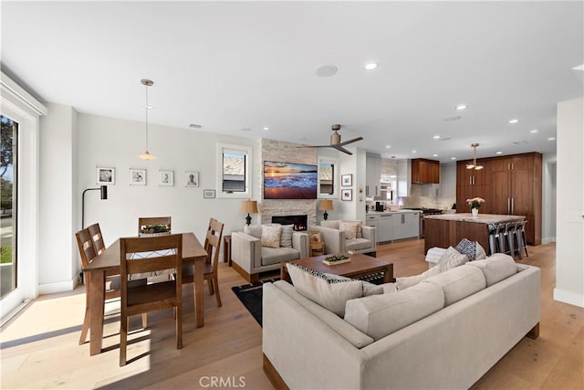 living area featuring baseboards, visible vents, light wood-style floors, a fireplace, and recessed lighting