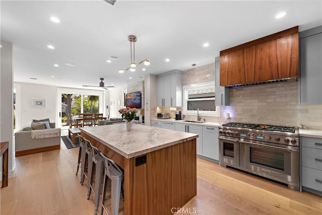 kitchen featuring light wood finished floors, double oven range, a sink, and a center island