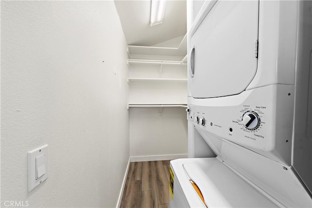 laundry room featuring laundry area, stacked washer / dryer, wood finished floors, and baseboards