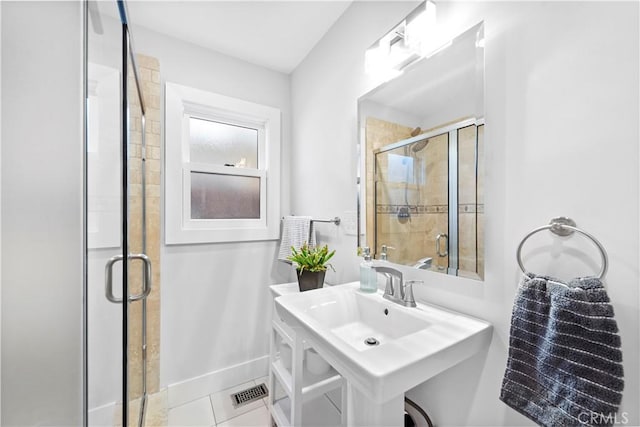 bathroom with a sink, tile patterned floors, a shower stall, and baseboards