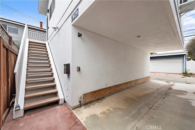 exterior space with stairs, a patio area, and stucco siding