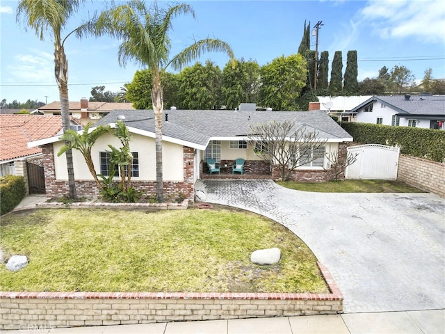 ranch-style home featuring driveway, brick siding, a front yard, and fence