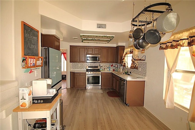 kitchen with stainless steel appliances, visible vents, light countertops, decorative backsplash, and light wood finished floors