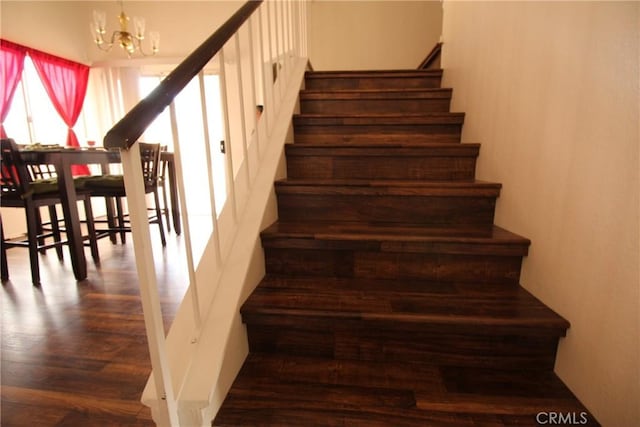 staircase featuring a chandelier and wood finished floors