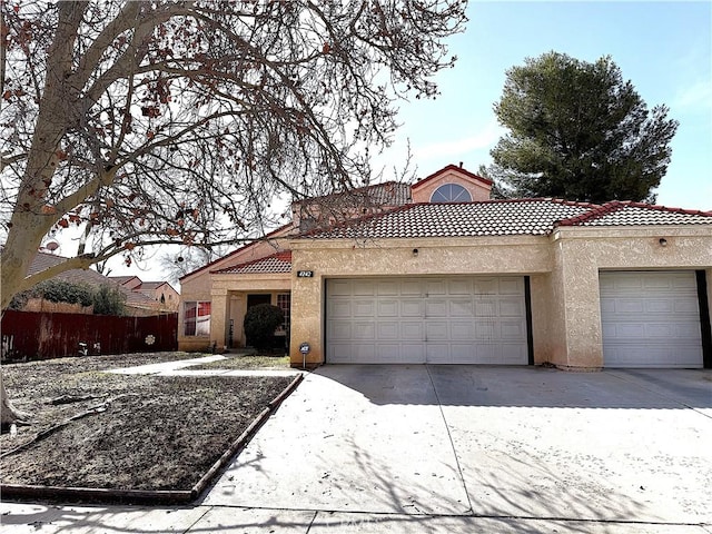 view of front of house with a garage, concrete driveway, a tiled roof, fence, and stucco siding