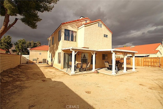 rear view of house featuring a patio area, a fenced backyard, a tile roof, and stucco siding