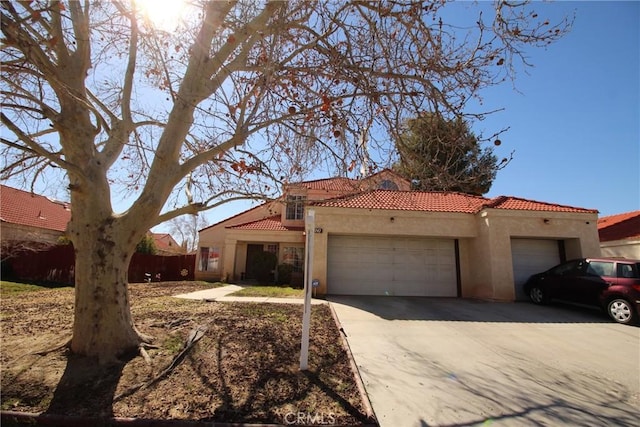 mediterranean / spanish home featuring concrete driveway, a tiled roof, an attached garage, and stucco siding