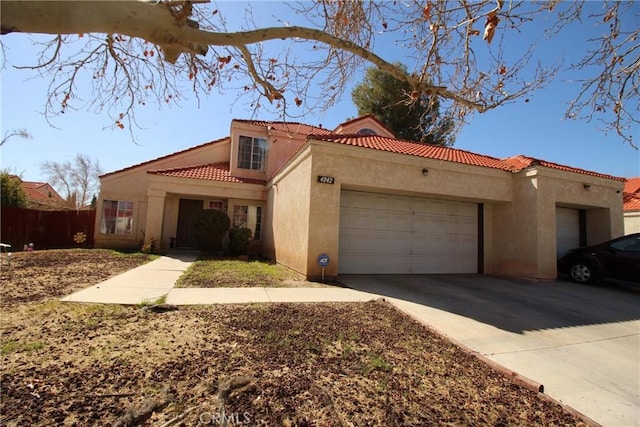 mediterranean / spanish house with a garage, concrete driveway, stucco siding, and a tiled roof