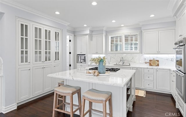 kitchen with dark wood-type flooring, a center island, a kitchen bar, white cabinetry, and gas cooktop