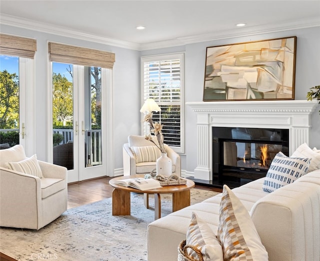 living area with french doors, crown molding, recessed lighting, a glass covered fireplace, and wood finished floors