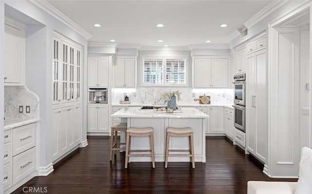 kitchen featuring a center island, a breakfast bar, visible vents, dark wood-type flooring, and white cabinets