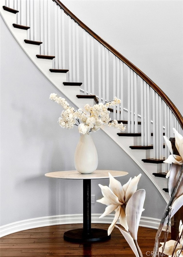 staircase featuring baseboards and wood finished floors