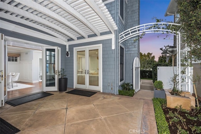 view of exterior entry featuring a patio area, fence, and french doors