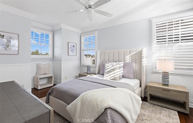 bedroom featuring a wainscoted wall, ornamental molding, wood finished floors, and a ceiling fan