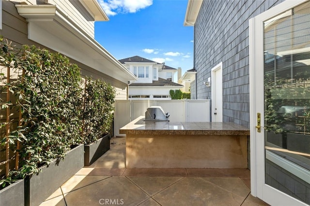 view of patio with exterior kitchen, grilling area, and fence