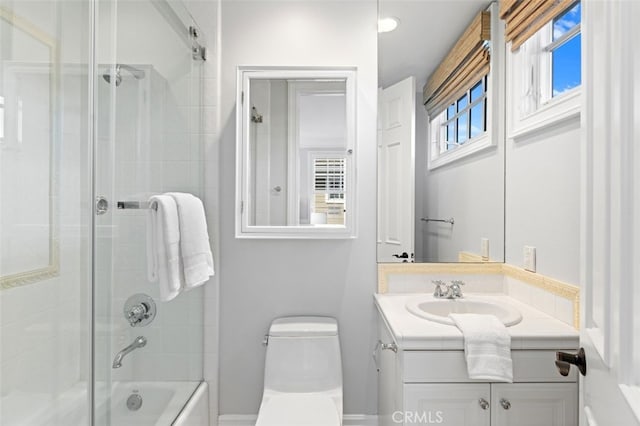 full bath with enclosed tub / shower combo, vanity, and toilet