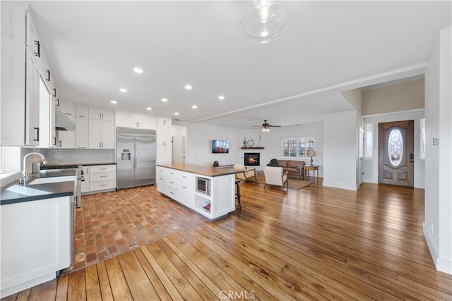 30927 Del Rey Rd, Temecula, CA 92591 - kitchen featuring built in refrigerator, open floor plan, dark countertops, a glass covered fireplace, and white cabinets