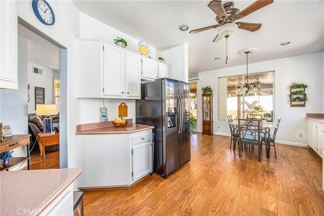 kitchen featuring ceiling fan with notable chandelier, visible vents, light wood-style floors, white cabinetry, and stainless steel refrigerator with ice dispenser