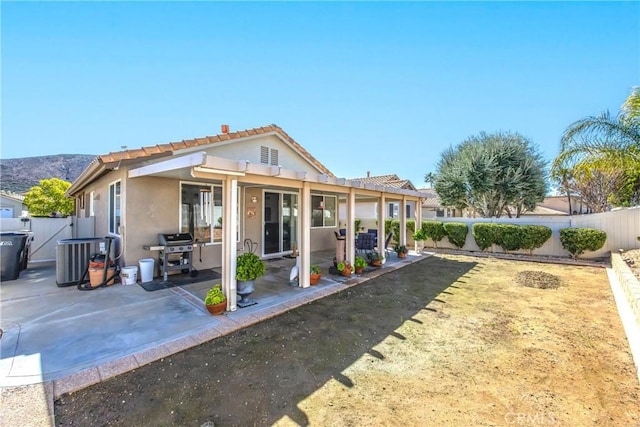 back of house with stucco siding, a patio, a fenced backyard, and central air condition unit