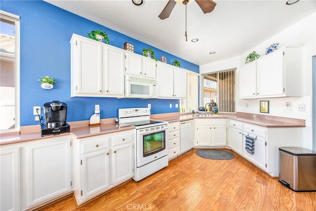 kitchen featuring white appliances, white cabinets, a sink, and light wood finished floors