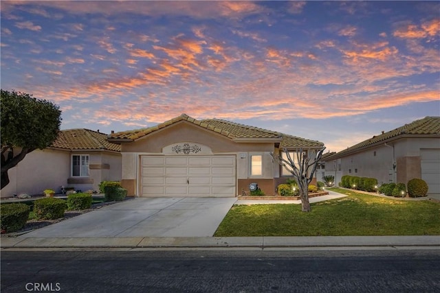 view of front of property featuring a garage, a yard, a tiled roof, and stucco siding