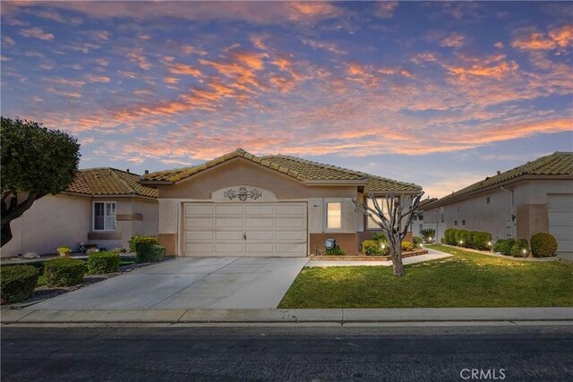 5855 Myrtle Beach Dr, Banning, CA 92220 - mediterranean / spanish house featuring stucco siding, a garage, a lawn, and a tiled roof