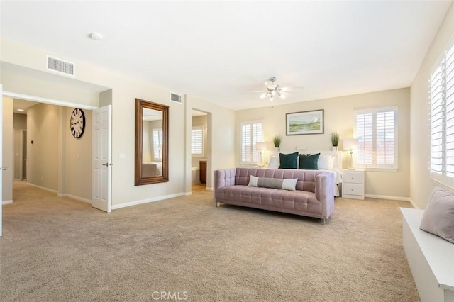 living room featuring baseboards, a ceiling fan, visible vents, and light colored carpet