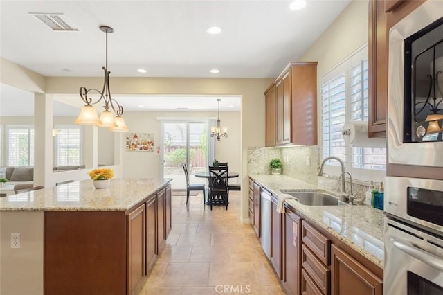 kitchen featuring brown cabinetry, a center island, visible vents, and a sink