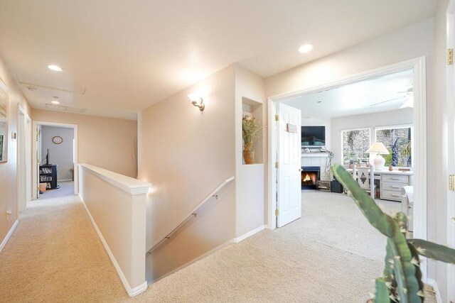 hall with carpet floors, recessed lighting, baseboards, and an upstairs landing