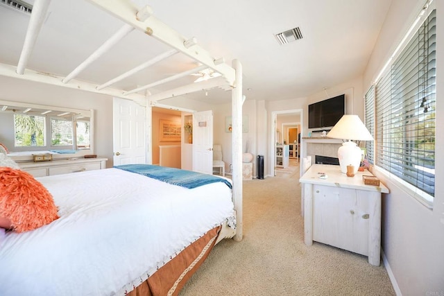 bedroom with visible vents, a fireplace, light carpet, and baseboards