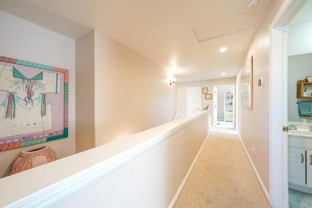 hallway with light carpet, baseboards, an upstairs landing, a sink, and recessed lighting