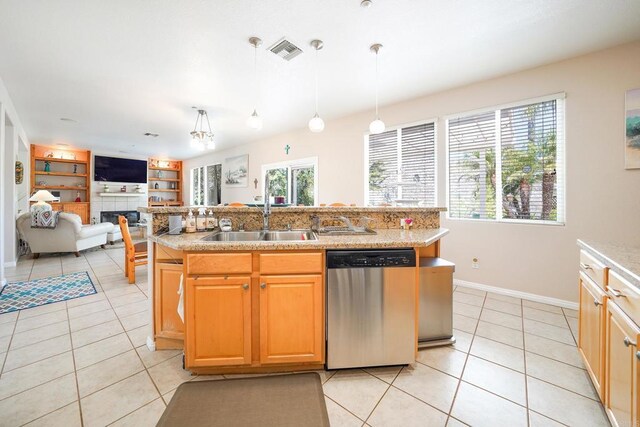 kitchen featuring light tile patterned floors, dishwasher, a tile fireplace, open floor plan, and a sink