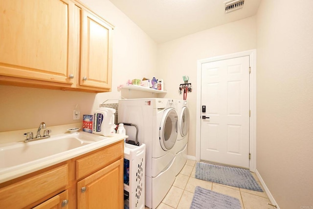 laundry room featuring washer and clothes dryer, visible vents, cabinet space, light tile patterned flooring, and a sink