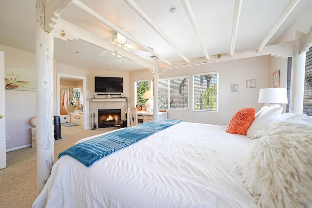 bedroom with carpet floors, beam ceiling, a fireplace, and baseboards