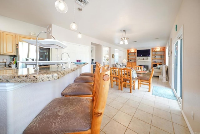 kitchen featuring light brown cabinetry, visible vents, hanging light fixtures, and light tile patterned flooring