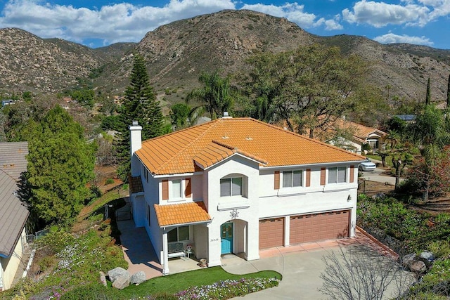 view of front of property with driveway, a mountain view, a tiled roof, and stucco siding